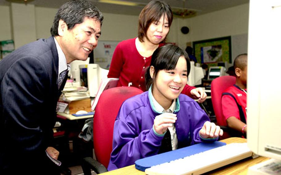 Yamauchi Junior High School eighth-grader Mami Matayoshi types on a computer at Kadena Middle School last week while Yamauchi principal Seitoku Kawasaki, left, and English teacher Kiyomi Miyagi look on.