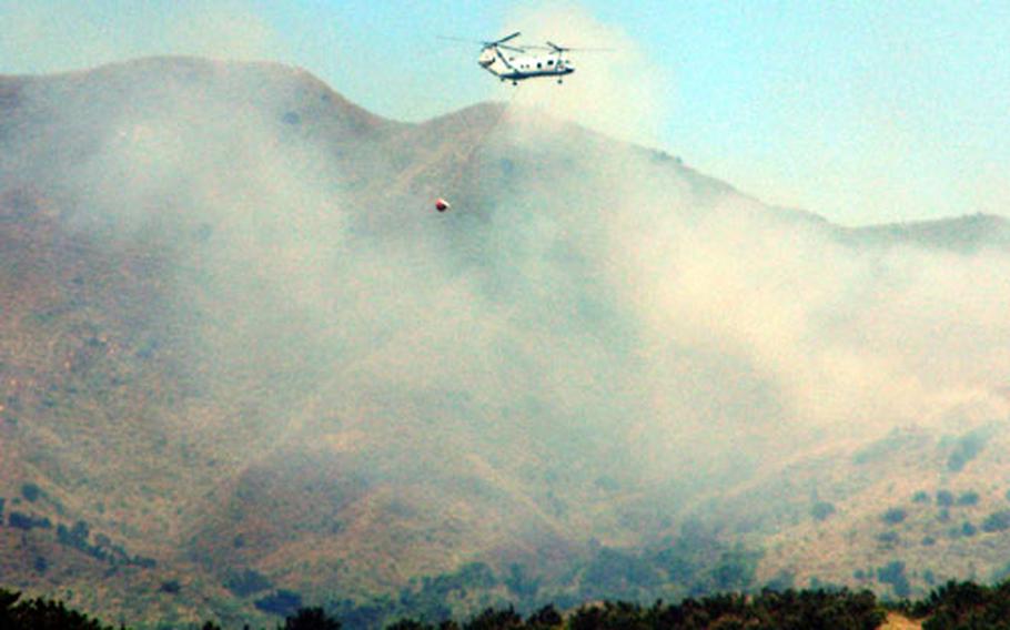 A Marine CH-46 helicopter dumps a load of water on a brush fire Tuesday at Camp Hansen, Okinawa.