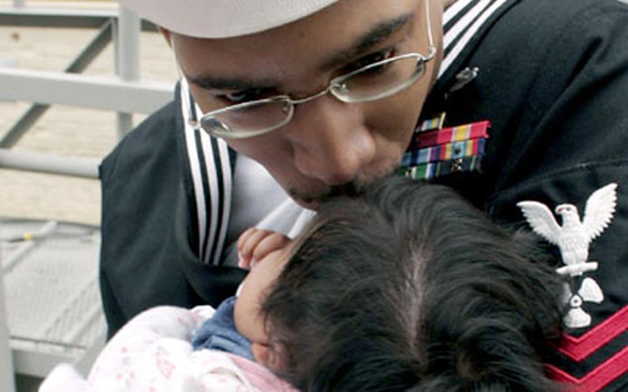 Petty Officer 2nd Class Donald Raymond hugs and kisses his new daughter, Ashley, moments after he disembarked the USS Essex at Sasebo.