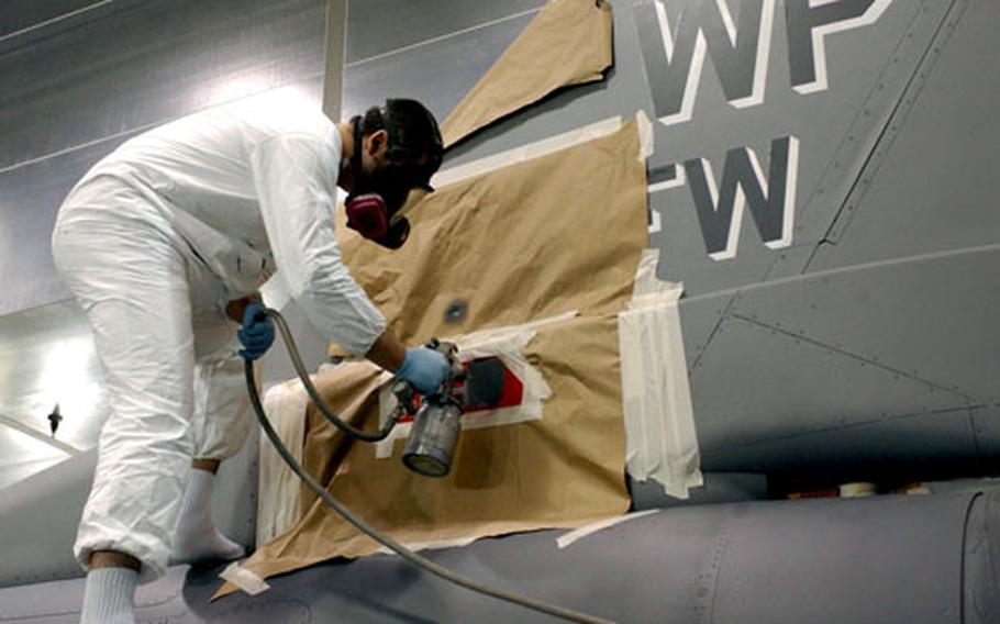 Senior Airman Josh Lanoi of the 8th Maintenance Squadron paints the tail of the F-16 fighter plane assigned to the wing’s commander.