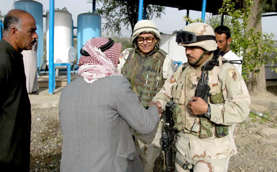 Staff Sgt. Rene Ortiz, right, of the 426th Civil Affairs Battalion, shakes hands with a local official in Bichigan, Iraq, after inspecting the filtration system, background, of a water system to be used by the small village.