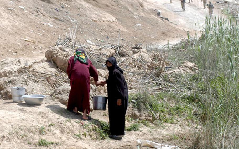 Women from the village of Al-Mashru, Iraq, collect water from an irrigation canal near their home on April 4.