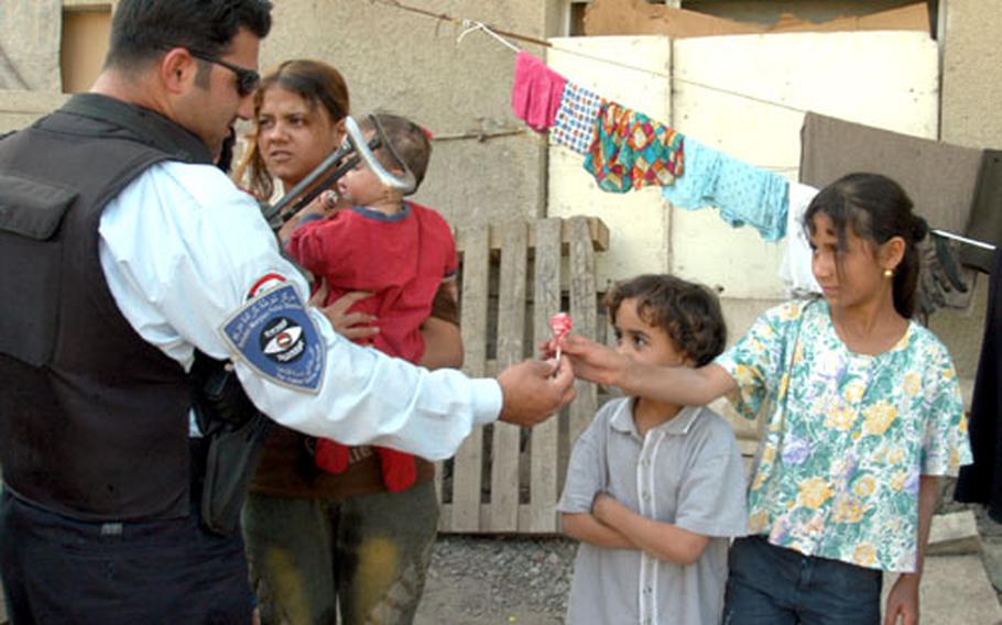 Iraqi policeman Mnieer, 24, hands out Blow Pop lollipops to children living in a run-down amphitheater inside Baghdad&#39;s International Zone. He said community policing is needed to gain trust of the community, a foreign concept to most Iraqis.