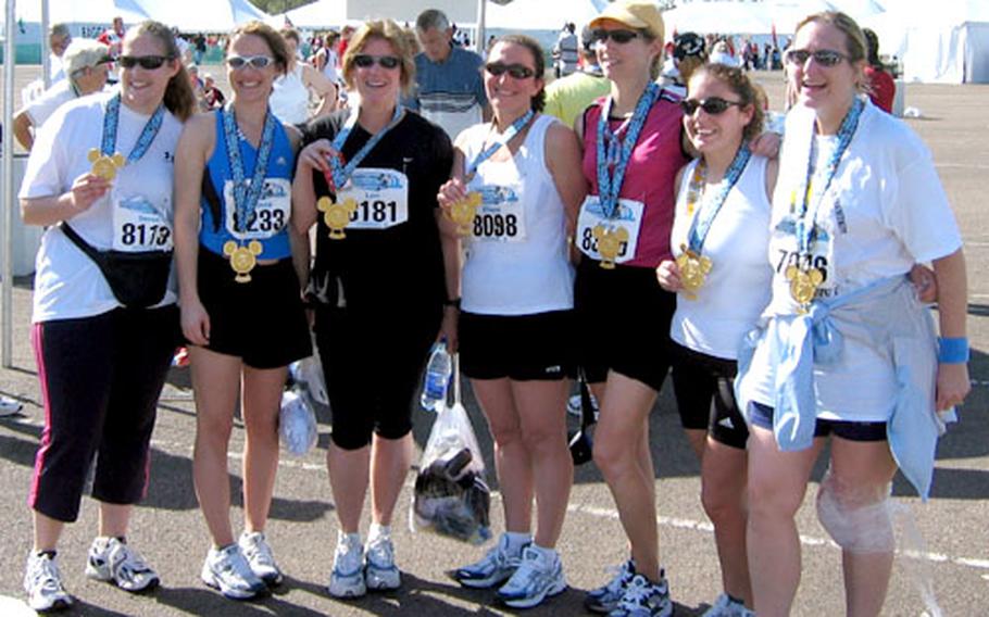 Smiling after running 26.2 miles and a year of training together while their husbands were deployed, 1st ID wives, from left, Devon Williams, Mindy Campbell, Lori Mitchell, Eliane Wentz, Sarita Garrison, Melissa Fitzgerald and Tracy Fass celebrate their completion of the Walt Disney World Marathon in Florida.