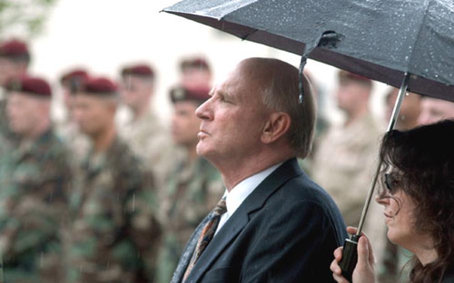 Steve Lindell and Rafaella Kilgore listen to a base chaplain over a loudspeaker in the parking lot of the Vicenza chapel during Tuesday&#39;s memorial service. About 100 soldiers and community members listened to the service outside in the rain because the chapel filled to capacity.