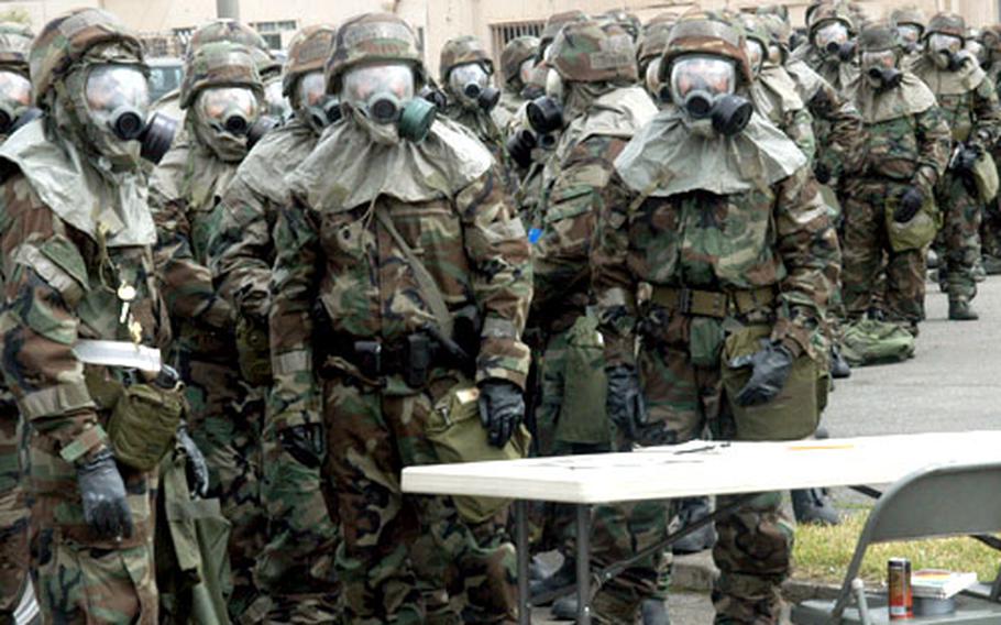 Yokota Air Base, Japan, airmen decked out in full mission-oriented protective posture, or MOPP, gear wait to enter a decontamination line set up on base Thursday in the aftermath of a simulated chemical attack. It was part of a three-day task evaluation of 374th Airlift Wing personnel, marked by various drills and procedural reviews.