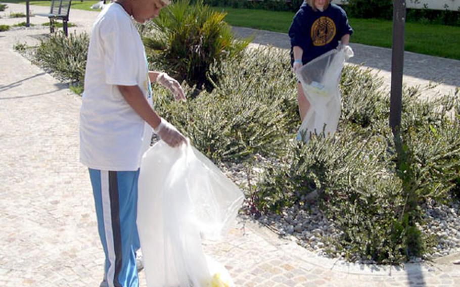 Classmates Kendall Olinger, right, and Channda Mitchell walk along one of the walkways leading between the apartment buildings at the Naval Support Activity Naples, Italy, Gricignano housing area. The small, green shrubs caught lots of trash, and the girls spent much of the late morning bent over picking it up during the base&#39;s annual Earth Day commemoration.