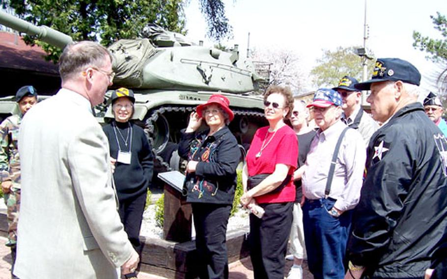 Second Infantry Division Museum Director William Michale Alexander, left, greets visiting Korean War veterans and family members Thursday at Camp Red Cloud, South Korea.