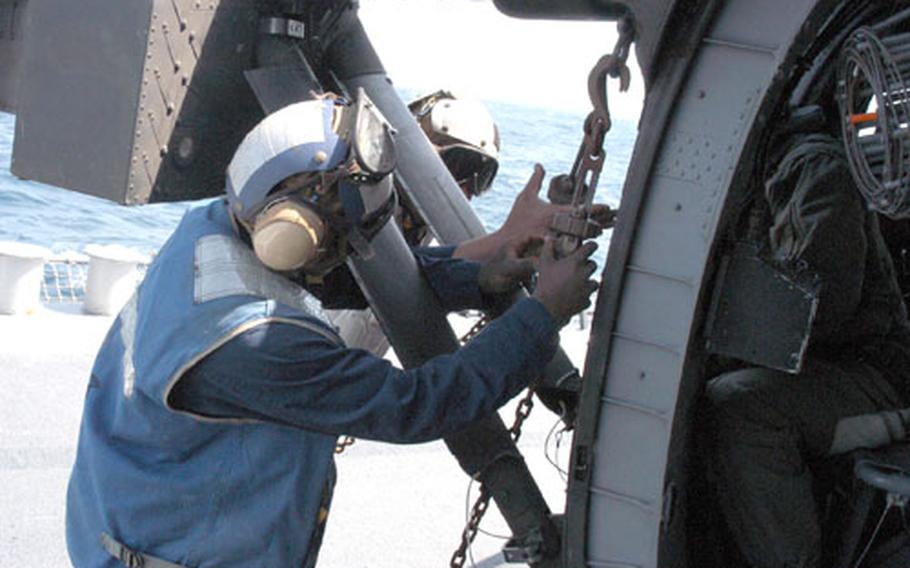 Sailors aboard the Wilbur attach chains to an Army Black Hawk during the deck landing training.