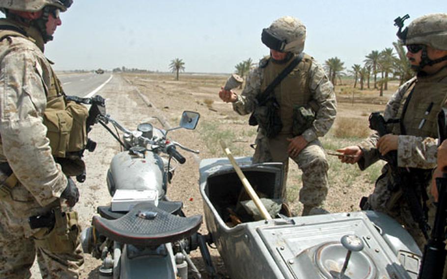 Gunnery Sgt. Jeff Dagenhart, leader of 2nd Platoon, Weapons Company of the 3rd Battalion, 8th Marine Regiment, stands with other Marines as they inspect a motorcycle seized from a suspected insurgent a few miles outside of Fallujah, Iraq.