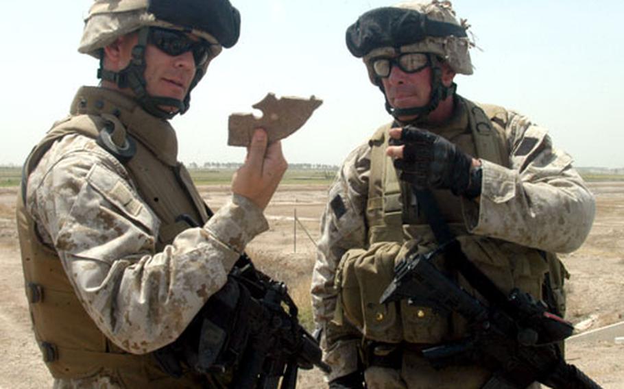 “Wanna see something scary?” Dagenhart, left, asked Capt. Ed Nevgloski, commanding officer of Weapons Company, as they look at a piece of metallic mine found in the sidecar of the motorcycle.