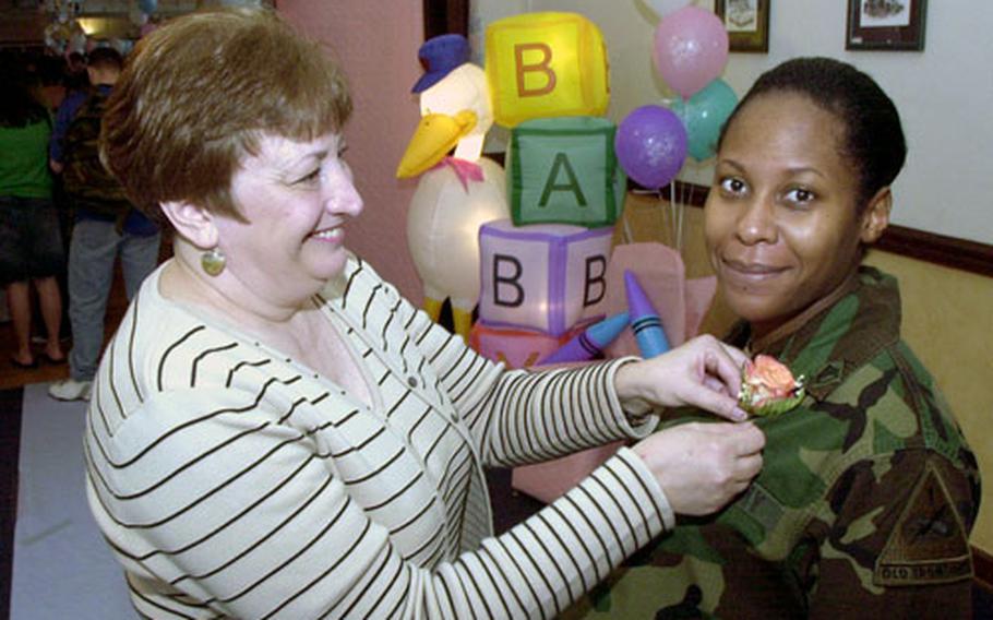 Teresa Tucker pins a pink rose corsage on Staff Sgt. Kakita Simpson as Simpson arrives at Baumholder’s giant Operation Iron Stork baby shower. Each expectant mother got a corsage courtesy of senior spouses on this 1st Armored Division base in Germany.