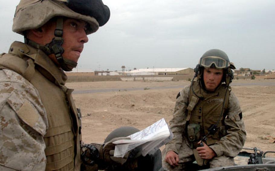 Gunnery Sgt. Brendan Slattery, left, looks over a road map of his area of responsibility — the 25 miles of Main Service Road Michigan — and discusses where Marines might set up vehicle checkpoints and observation posts along the way with track commander Sgt. Frank Drake (not shown), and Cpl. Chris Campbell, right, the driver of the Amphibious Assault Vehicle.