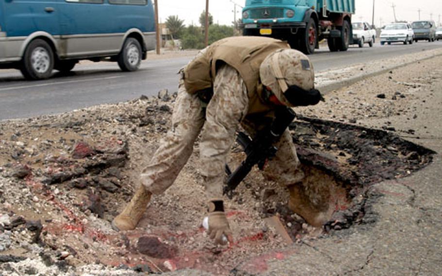 Slattery marks the crater left earlier by a roadside explosion on Main Service Road Michigan with red spray paint, which not only marks the location, but lets Marines monitor the hole to see if anyone tampers with it or tries to hide another explosive. Insurgents frequently plant roadside bombs on the road.