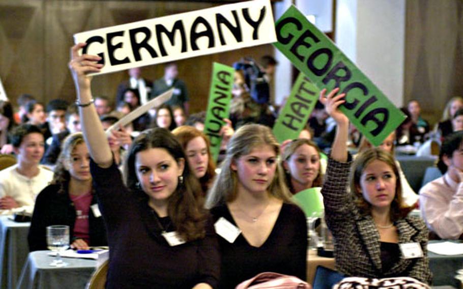 Students representing countries from around the world hold up their placards during a vote Tuesday at the Model United Nations conference at Ramstein Air Base, Germany.