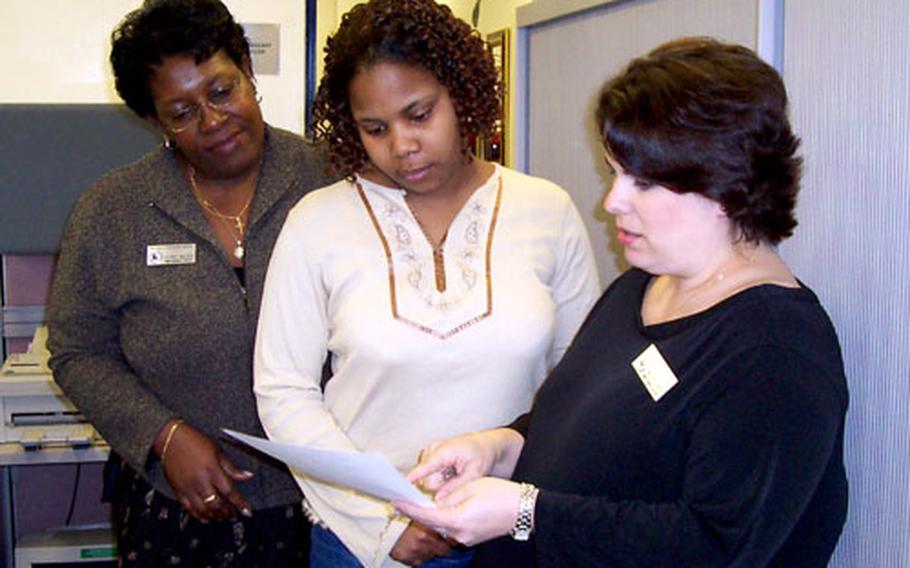 Latanya Fields, center, talks over her application for a job at the commissary at RAF Menwith Hill, England, with DECA Europe human resources workers Glenda Malden, left, and Amoreena Barks. Malden and Barks were in England to recruit for commissary workers.