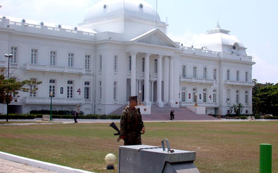 In April 2004, Cpl. Juan Farris, of 1st Platoon, Lima Company, 3rd Battalion, 8th Marines stands watch at the gate of the palace in Port-au-Prince, Haiti.