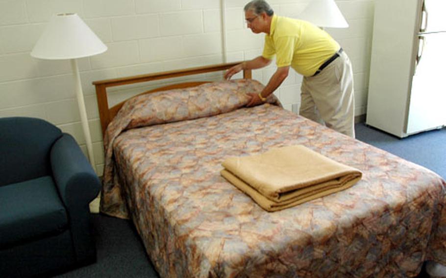 Bachelor Housing Division official Richard Marquez fluffs the pillows on a double bed Wednesday in a room designated for bachelor officers rated 0-3 and below at a recently renovated barracks at Marine Corps Air Station Iwakuni.