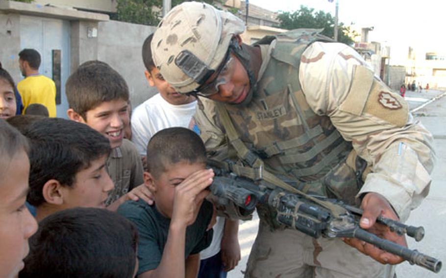 1st Lt. Jason Stanley, 26, the fire support officer with Company C, 1st Battalion, 24th Infantry Regiment, lets Iraqi children look through the scope of his rifle as soldiers patrol the Yarmook neighborhood of Mosul on Wednesday.