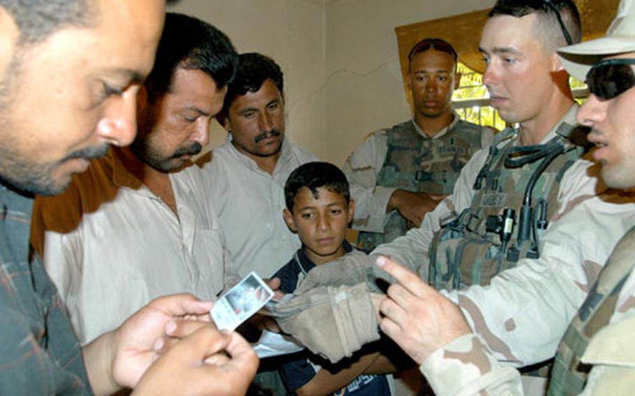 Capt. Scott Cheney, commanding officer of Company C, 1st Battalion, 24th Infantry Regiment, hands out a card with phone numbers that families can call if they spot suspicious activity.