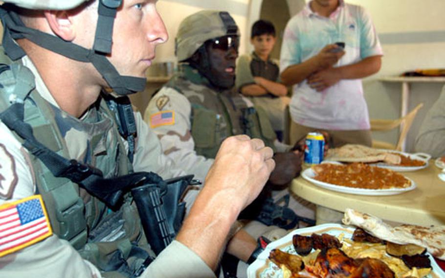 Capt. Jeff Vanantwerp, left, commanding officer of Company A, 1st Battalion, 24th Infantry Regiment, shares lunch with a restaurant owner as they discuss getting the residents more involved in defense of the neighborhood.