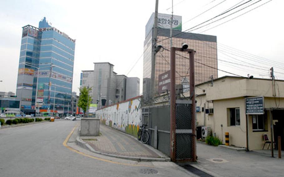 Newly built glass office towers in downtown Uijongbu City dwarf the entrance to the south post at Camp Falling Water, South Korea.