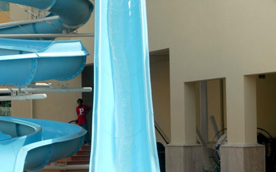 A young girl splashes into the pool after a quick trip down one of two water slides at the new Naval Air Station Sigonella pool.