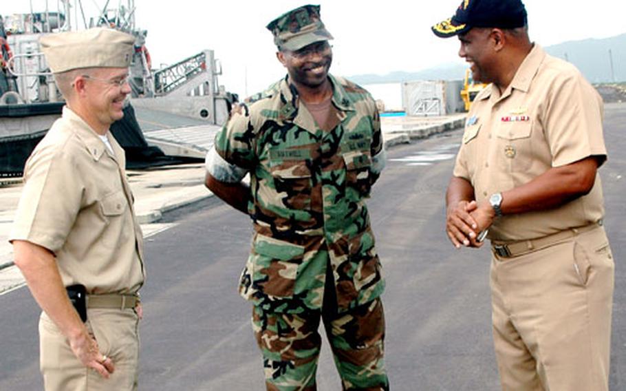 Rear Adm. Victor Guillory, right, talks with Chief Warrant Officers Ron Herb, left, and Curtis Maxwell on the apron at Sakibe Laydown Facility, home of Assault Craft Unit Five, Western Pacific Detachment.