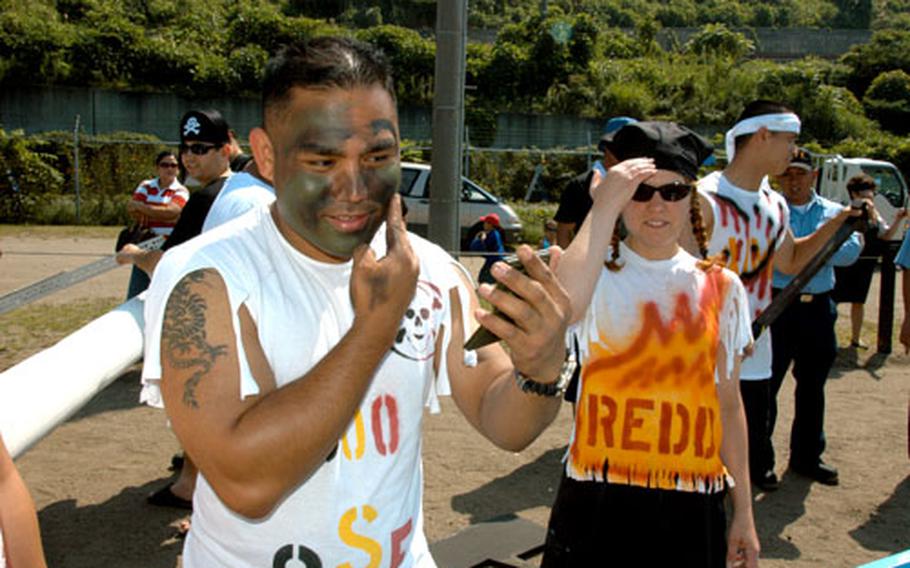 Petty Officer 2nd Class Erickson Arucan, left, puts on his game face prior to the start of the boat regatta.