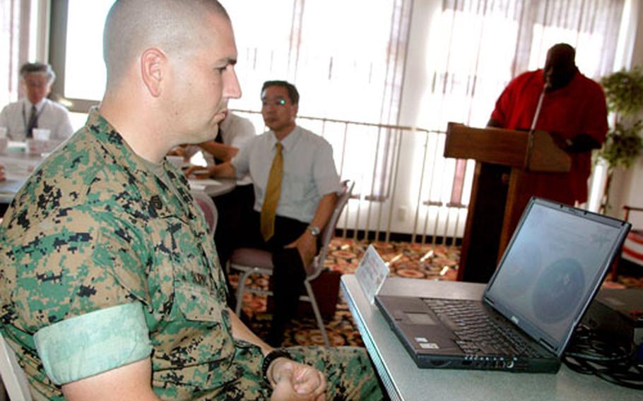 Staff Sgt. Randy Scifo, anti-terrorism and force protection chief at Marine Corps Air Station Iwakuni, controls a Power Point projection coinciding with remarks by Andrew Samuels, antiterrorism and force protection officer.