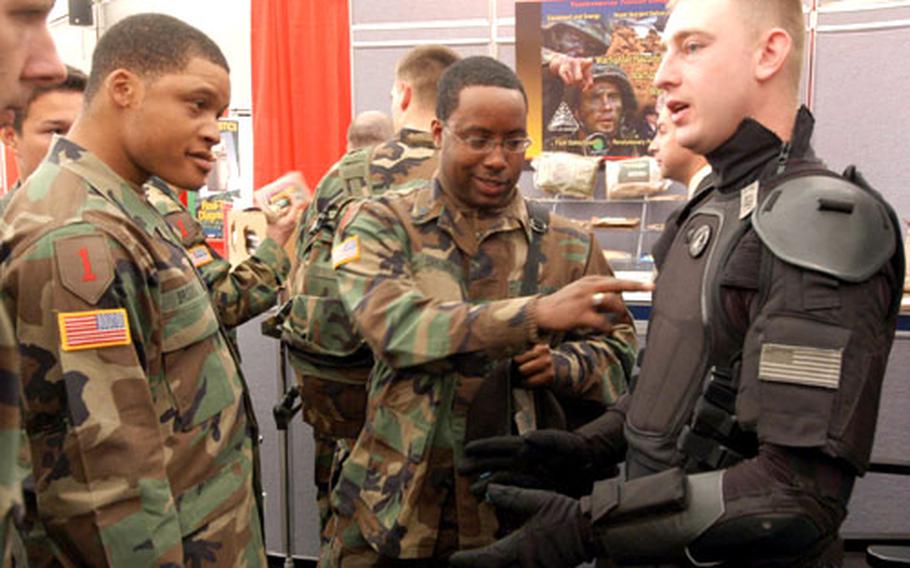 Spc. Sterling Brown, center, of 1st Battalion, 33rd Field Artillery out of Bamberg, Germany, touches the body armor of a Future Warrior Concept uniform worn by Staff Sgt. Robert Atkinson. The body armor of the uniform of the future will be made of a gel-like substance that hardens on impact. It is hoped that uniform will become available in the 2025-2030 time frame.