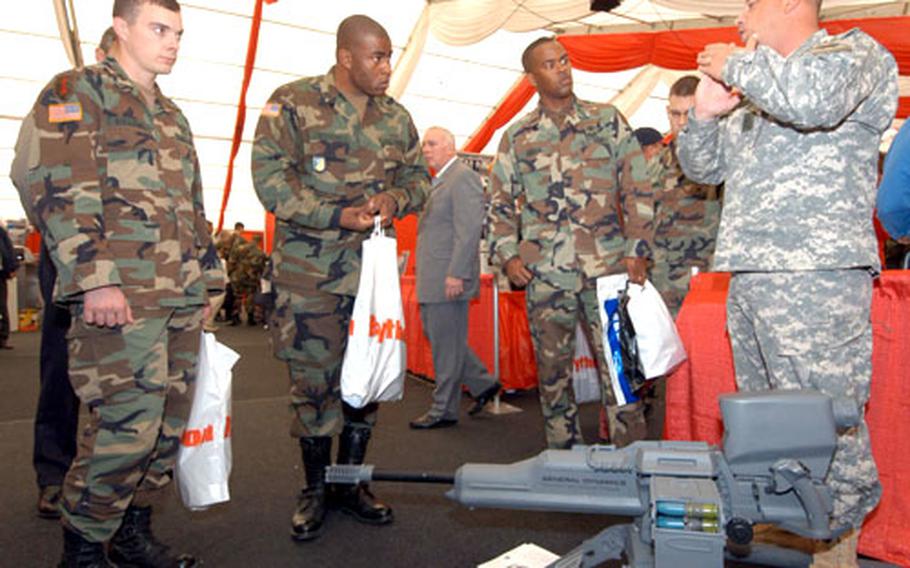 Sgt. 1st Class Richard Fairman, right, of the Unit of Action Maneuver Battle Lab at Fort Knox, talks about the light-weight XM312 .50 caliber machine gun at the Land Combat Expo in Heidelberg on Wednesday. The gun, with tripod and 100 rounds of ammunition, weighs in at 94 pounds.