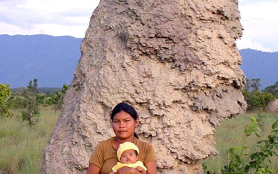 Cathy Rice’s biological mother, Seleen Mario, holds Cathy in July in front of a giant termite mound near their tribe’s home in Moco Moco Village.