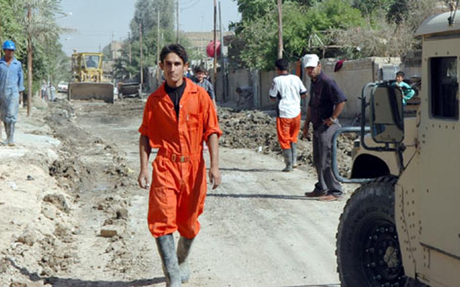 Jumpsuited workers fill the streets of Tissa Nissan, a poor neighborhood in eastern Baghdad. The workers are installing the area&#39;s first underground sewer system.