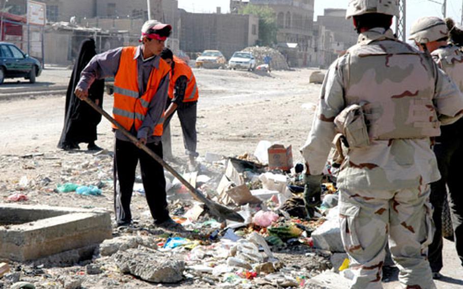 Local workers shovel trash from collection points into trucks in Sadr City.