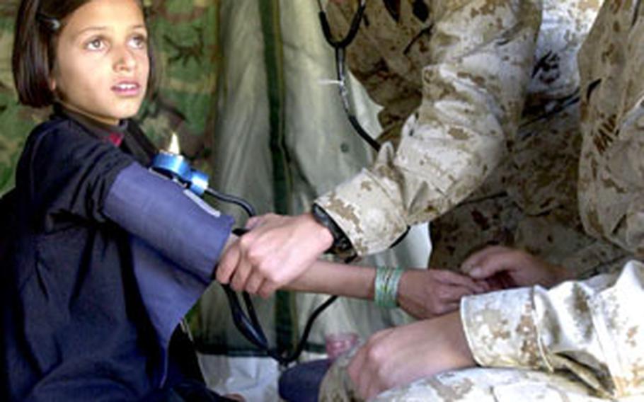 Seaman Lacy Helphenstine, right, watches as Petty Officer 3rd Class Fridalyn Ocampo takes the blood pressure of a young Pakistani girl Thursday in the triage tent of a field hospital from III Marine Expeditionary Force, which has been set up in Shinkiari, Pakistan.