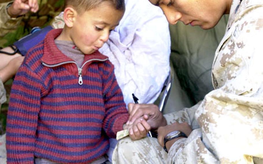 Seaman Garrett Castro, corpsman with 3rd Medical Battalion, checks the pulse of a young Pakistani boy Thursday.