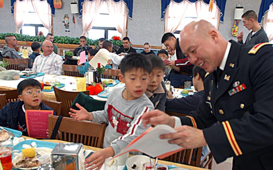 Second Lt. Tae H. Rose with Headquarters Headquarters Company, 1st Heavy Brigade Combat Team, 2nd Infantry Division hands out Thanksgiving cards to children from the My Home Orphanage at Camp Hovey, South Korea, on Thursday.