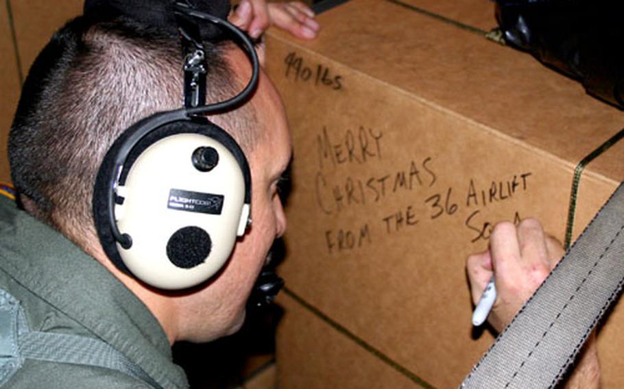 Master Sgt. Kevin Saquilan, a loadmaster, writes a Christmas message on one of the boxes to be dropped to residents of the outer islands of Chuuk State on the Federated States of Micronesia. The box later was parachuted as part of the 2005 Christmas Drop from a C-130 transport plane crewed by members of the 36th Airlift Squadron of the 374th Airlift Wing based in Yokota Air Base, Japan.