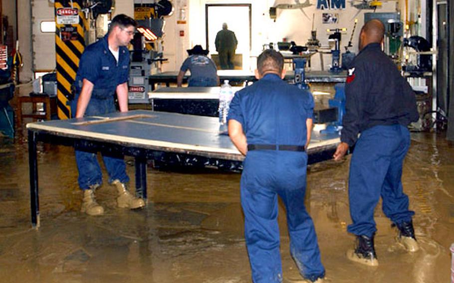 Sailors from the aircraft intermediate maintenance department move equipment damaged by this week’s flooding at NAS Sigonella.