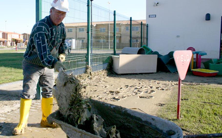 Rosario Russo, an Italian contractor with Lotus, shovels mud Monday morning from the playground of the Child Development Center.