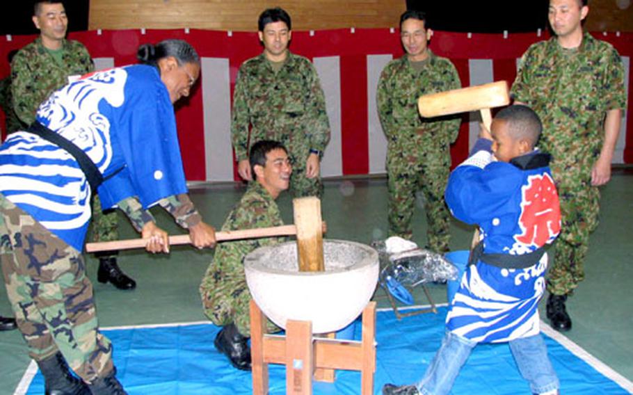 Army Lt. Col. Maria Drew, 58th Signal Battalion commander, pounds rice with her son, Zulymon, 6, during a ceremony Wednesday at the Japan Ground Self-Defense Force&#39;s Camp Naha.