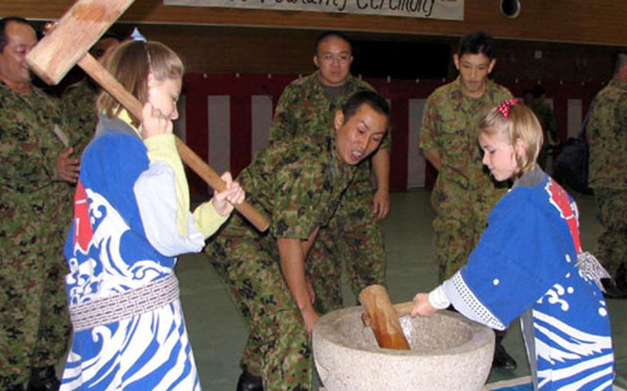 Meredith Bartholomew, 12, and her sister McKenna, 9, daughters of Chief Warrant Officer Benjamin Bartholomew, director of the III Marine Expeditionary Force Band, take their turns at pounding mochi.