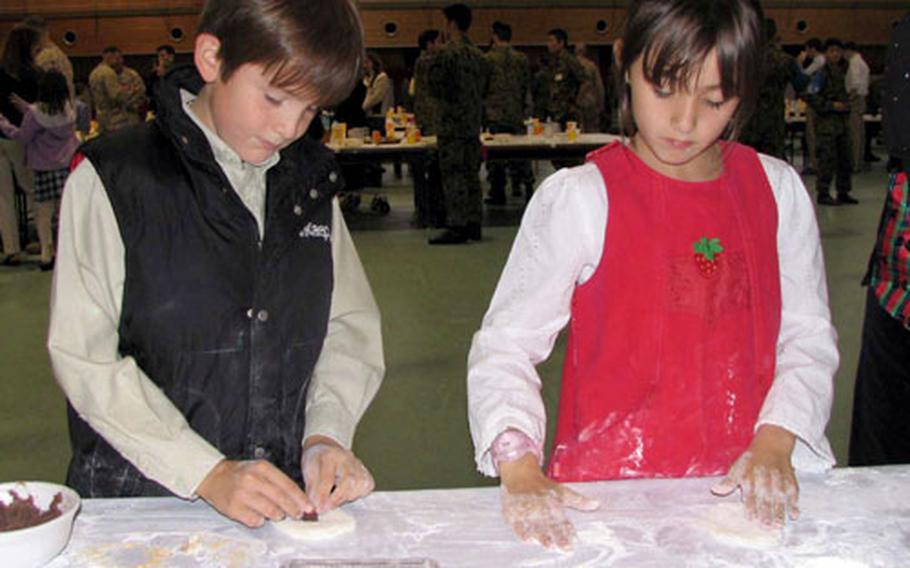 Tristan Walker, 9, and Ana Walker, 8, try their hand at making mochi balls from pounded rice and sweet beans.