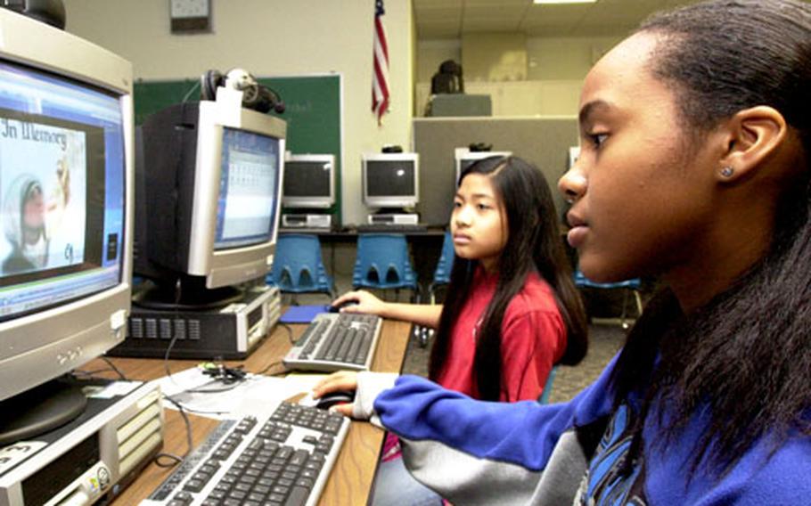 Amelia Earhart Intermediate School sixth-graders Tisha Carlton, foreground, and Annabel Posis look at Tisha’s picture show of Mother Theresa, which she completed for a school project. The show includes photos and background music, with a narration by Trisha.