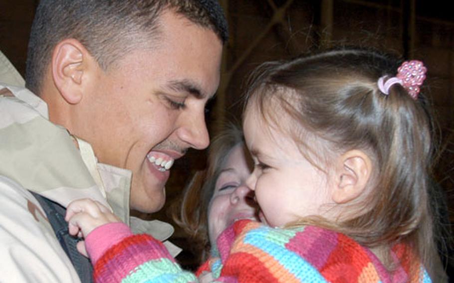 Staff Sgt. Adam Watson of the 35th Civil Engineer Squadron embraces his 2-year-old daughter, Kenna, and wife, Ashley, Wednesday night at Misawa Air Base, Japan. Watson was among the 70 civil engineer airmen returning from northern Kuwait.