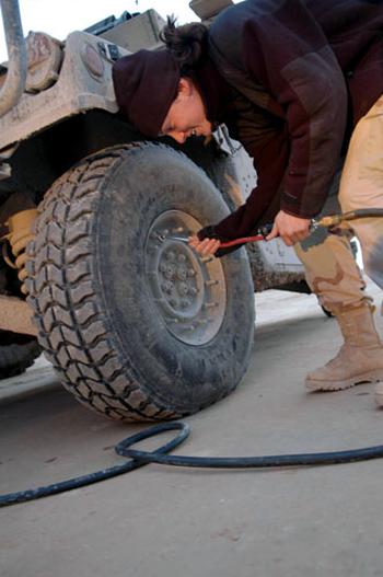 Spc. Shana Poulin, 23, a tactical movement team driver, pumps air into the tires of her vehicle in western Iraq.