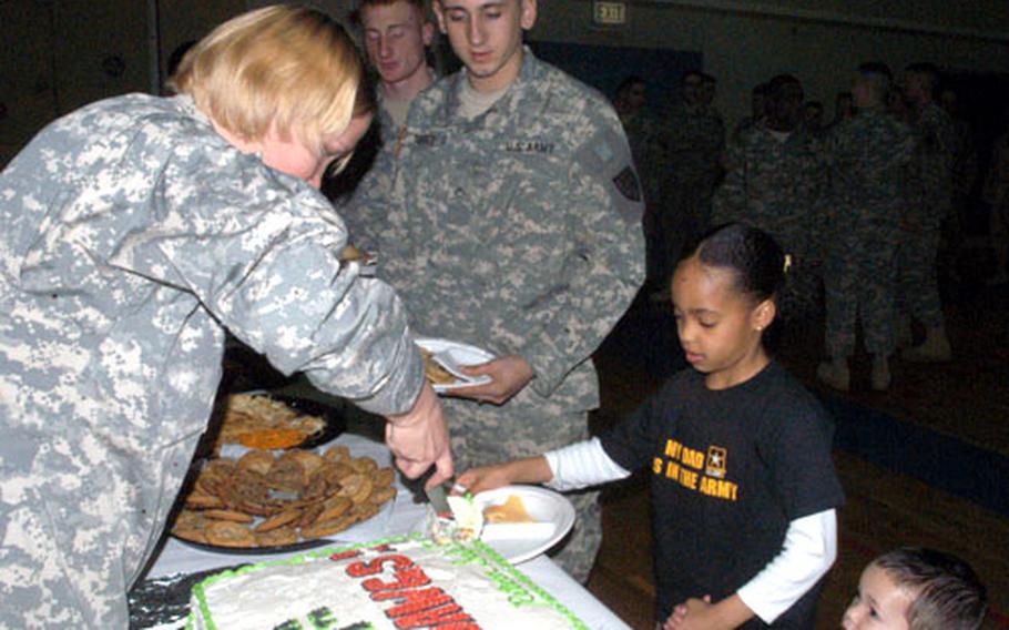 Nine-year-old Brianna Wills holds the hand of her 2-year-old brother, D.J., in front of Spc. Jose Torres as cake is served Thursday at a predeployment ceremony for the Stuttgart-based 554th Military Police Company. Brianna and D.J. are the children of Sgt. David Wills of Headquarters Platoon.