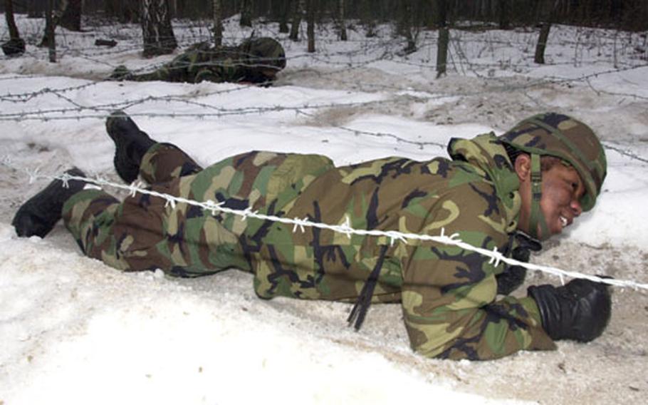 A 191st Ordinance Battalion soldier crawls under barbed wire on the obstacle course.