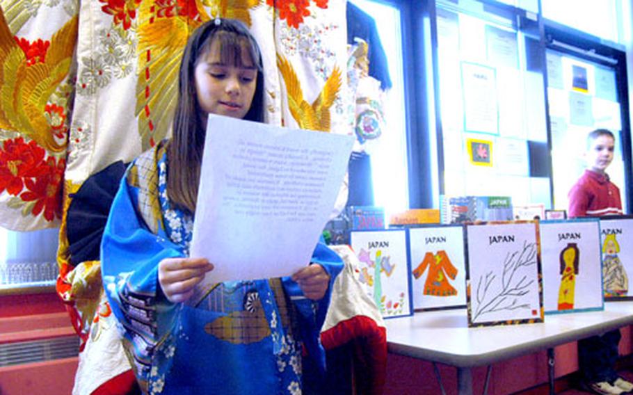 Alyssa Carney, 8, reads her presentation about kimonos, the traditional form of Japanese dress like the one she&#39;s wearing, last week at the Lakenheath Elementary School. Hanging behind Carney is an adult-sized version of the decorative robe.